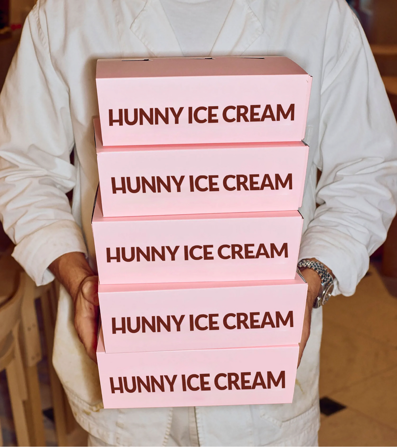 Stack of pink 'HUNNY ICE CREAM' boxes held by a person.